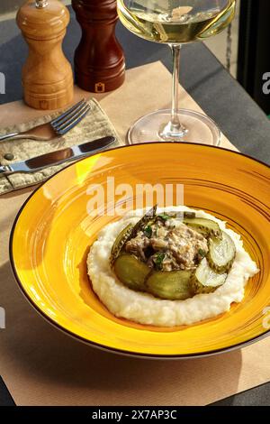 Beef stroganoff with mashed potatoes and pickles on yellow plate Stock Photo