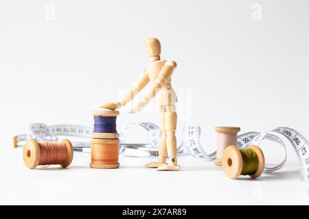 Spools of thread and measuring tape and sewing scissors and a wooden man on a white background, sewing Stock Photo