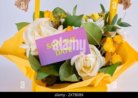 SAVE THE DATE concept on a purple card inserted into a bouquet of roses Stock Photo