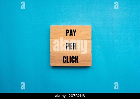 Pay per click words written on wooden blocks with blue background. Conceptual pay per click PPC symbol. Copy space. Stock Photo