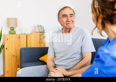 Female caregiver talking with senior male patient at nursing home. Stock Photo