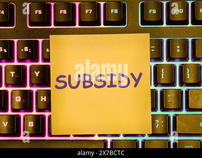 Business and finance concept. SUBSIDY the word on a yellow sticker lying on the keyboard with a colored backlight Stock Photo