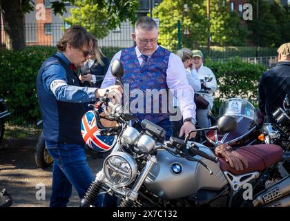 Warrington, Cheshire, UK. 19th May, 2024. UK - The Distinguished Gentleman's Ride (DGR) unites classic and vintage-styled motorcycle riders from all over the world to raise funds and awareness for prostate cancer research and men's mental health. A group of motorcycle riders from around Warrington dressed in their finest suits and ties, met at their local motorcycle dealer and then rode through the town centre before heading out of town and through a combination of villages and towns. Talk about the motorcycles before the ride Credit: John Hopkins/Alamy Live News Stock Photo