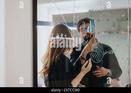Business professionals collaborating and brainstorming with sticky notes on glass wall Stock Photo