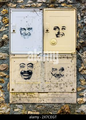 Stenciled faces on electricity meter boxes - Argenton-sur-Creuse, Indre (36), France. Stock Photo