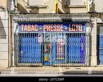 Sliding expanding metal security grille covering front of tobacconist, newsagent and betting shop - Argenton-sur-Creuse, Indre (36), France. Stock Photo