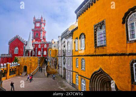 The brightly colored clocktower in the convent section with the Courtyard of Arches and private chapel of the Pena Palace or Palácio da Pena historic palace castle in Sintra, Portugal. The fairytale castle palace is considered one of the finest examples of 19th century Portuguese Romanticism architecture in the world. Stock Photo