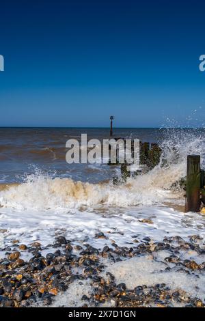 Waves crashing against a wooden groyne in Trimingham, North Norfolk, UK in Portrait Stock Photo
