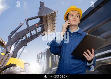 Female engineer with a digital tablet on the background of construction machines. Stock Photo