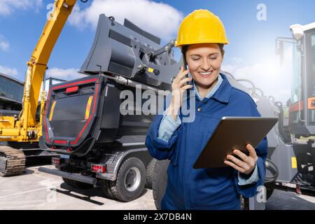 Female engineer with a digital tablet on the background of construction machines. Stock Photo