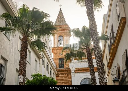 The 18th-century Baroque style Iglesia de la Palma on Calle Virgen De La Palma a palm tree lined pedestrian street known for restaurants and cafes in Cadiz, Spain. Cádiz is one of the oldest continuously inhabited settlement in Europe, founded by the Phoenicians in about 1100 BC. Stock Photo