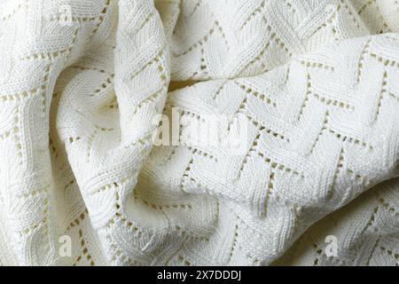 A white knit blanket with a pattern of zigzags. The blanket is soft and cozy, perfect for snuggling up on a cold day Stock Photo