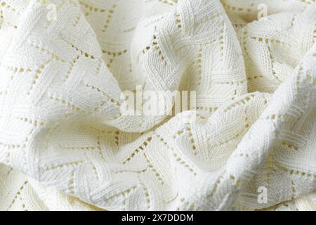 A white knit blanket with a pattern of zigzags. The blanket is soft and cozy, perfect for snuggling up on a cold day Stock Photo