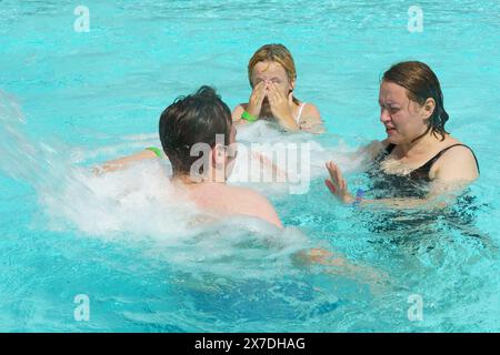 A group of individuals, likely a family, engage in playful activities in a swimming pool, enjoying the water and perhaps utilizing the hydromassage fe Stock Photo
