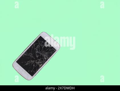 Broken mobile phone with cracked display on light green Stock Photo