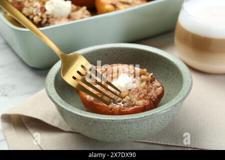 Eating tasty baked quince with nuts and cream cheese at table, closeup Stock Photo