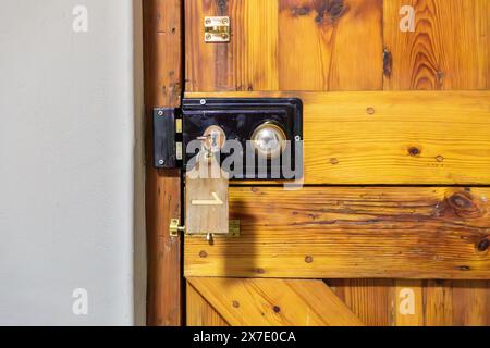 Wooden door with an old handle and locking mechanism. Key in the lock with the Number 1 written on the keychain.  Concept for an old hotel door. Stock Photo