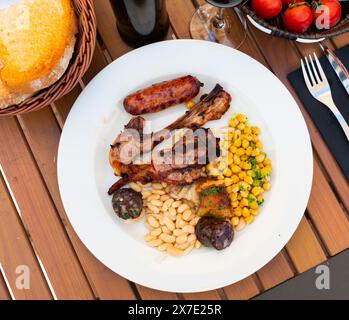 Lamb ribs on bone, sausage, piece of black pudding are complemented with stewed beans Stock Photo