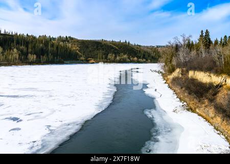 North Saskatchewan river bent in spring season with river water still frozen and open water stream breaking ice along river bank Stock Photo