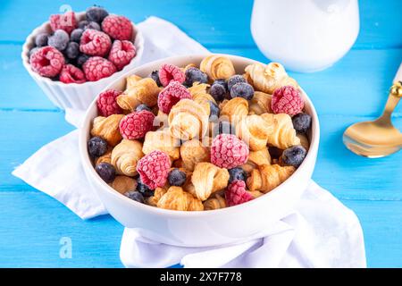 Tiny breakfast croissants cereals with fresh berries and milk. Bowl portions with trendy fresh baked mini petite croissants with raspberry and blueber Stock Photo
