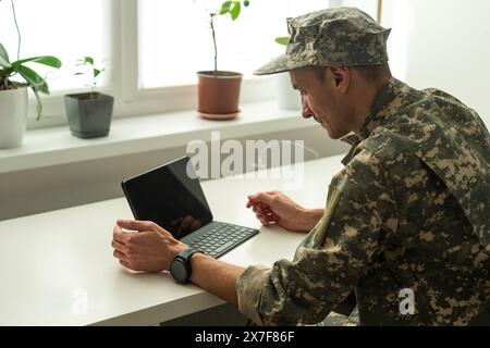Caucasian soldier in army uniform in front of computer feeling happy and excited. American soldier receiving good news. Stock Photo