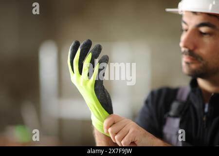 Construction worker putting a yellow protection glove in a house under reform Stock Photo