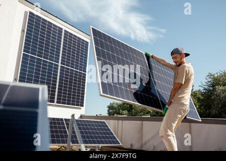 Man installing solar panels on a rooftop Stock Photo