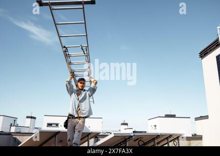 Man carries ladder during solar panels installation Stock Photo