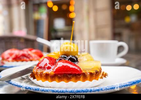 Mix fruit tart on dish and hot coffee served  in a cafe, famous refreshment and sweet for meeting place. Fruit tart with cup of coffee on table in caf Stock Photo