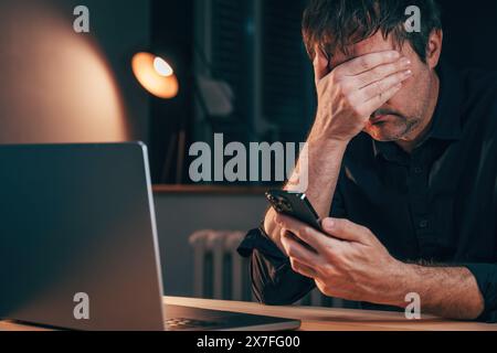Sad unhappy disappointed freelancer reading worrying text message on smartphone, selective focus Stock Photo