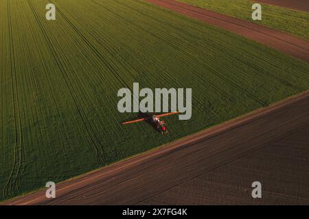 Wheat crops protection, aerial shot of agricultural tractor with fungicide sprayer attached in field, high angle view Stock Photo