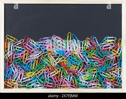Background with a black board with colorful paper clips and copy space Stock Photo