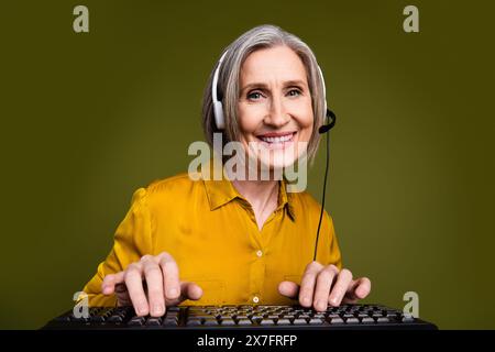Photo of charming positive woman wear shirt working client support service typing keyboard isolated khaki color background Stock Photo