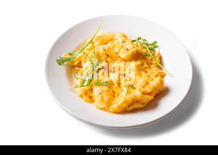 Scrambled eggs with arugula on white plate isolated on white background. Healthy breakfast - fluffy scrambled eggs, design element. Stock Photo