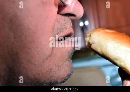 Profile view of a man wearing glasses about to eat a burger. Stock Photo