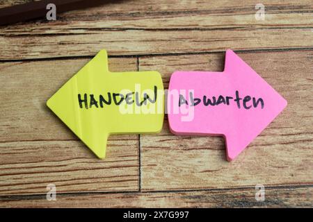 Concept of Learning language - German. Haldeln or Abwarten it means Hold on or wait written on sticky notes. German language isolated on Wooden Table. Stock Photo