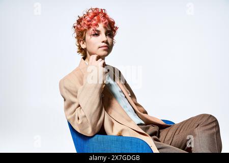 A woman with red hair, dressed extravagantly, sitting in a blue chair. Stock Photo