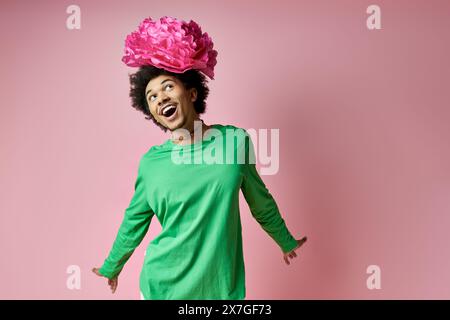 A joyful man with curly hair wearing a crown of pink flowers on her head against a vibrant backdrop. Stock Photo