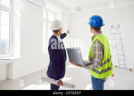 Young foreman discussing with architect design project or repair of new apartment with laptop Stock Photo
