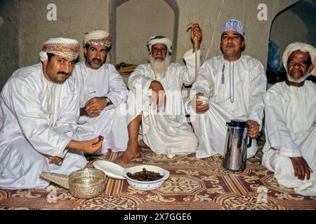 Nizwa, Oman, Arabian Peninsula, Middle East - Omani Men Having Dates and Coffee at Nizwa Fort. Stock Photo