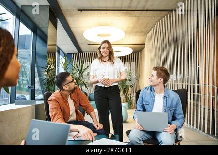 A diverse group of colleagues sit around a table with laptops, collaborating on projects and discussing ideas. Stock Photo
