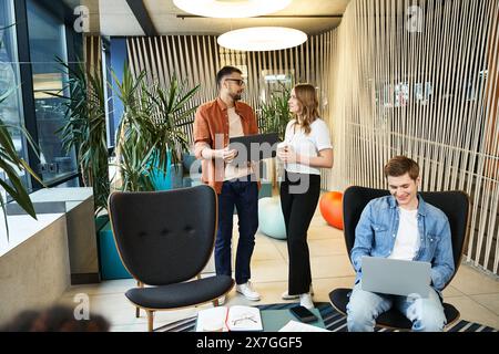 A group of colleagues engaged in a modern business lifestyle, standing around with laptops in a coworking space. Stock Photo