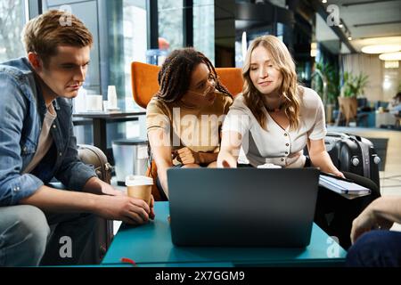 Multicultural colleagues gather around a laptop in a hotel lobby during a corporate trip, discussing business strategies. Stock Photo