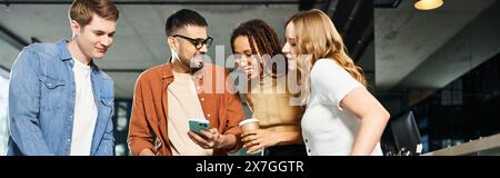 Multicultural colleagues in casual clothes stand together in a hotel lobby, engrossed in a cell phone. Stock Photo