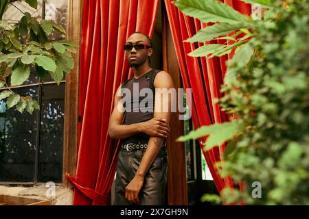 A handsome African American man stands confidently in front of a rich red curtain. Stock Photo