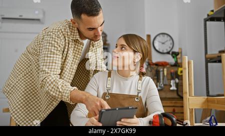 Man and woman working together in a carpentry workshop discussing a project on a tablet. Stock Photo