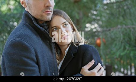 A loving couple embraces outdoors among green foliage, showcasing a tender moment between a man and a woman. Stock Photo