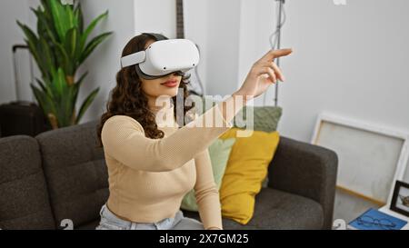 Young woman wearing vr headset interacts with virtual content in her modern living room Stock Photo