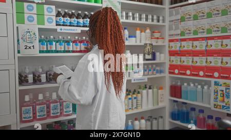 African american pharmacist woman reading medication in a modern pharmacy store Stock Photo