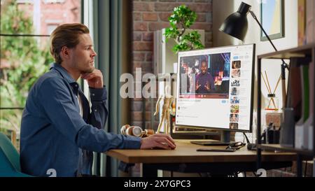 Handsome Man Watching Video Sharing Service Mock-up Where African American Influencer Talks About Lifestyle. Celebrity Blogger Having fun. Interface with Related Streams, Likes, Comments. Stock Photo